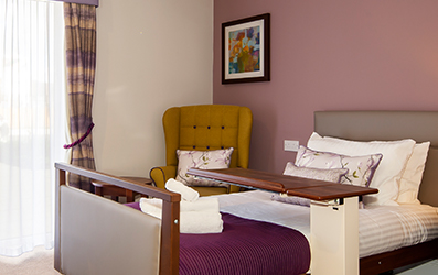 A profiling bed and an armchair in one of the bedrooms at Penrose Court Care Home