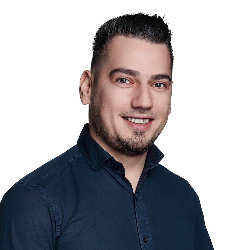 daniel home manager smiling wearing a black shirt in front of a white background
